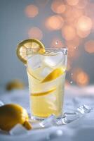Refreshing lemon drink with ice and lemon slices against a blurred background photo