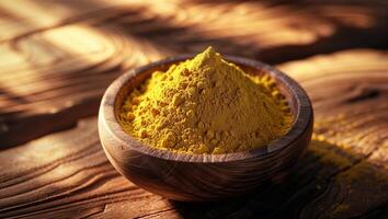 Golden turmeric powder in a wooden bowl resting on a rustic wooden table photo