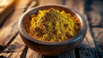 Bright yellow turmeric powder in a wooden bowl on a rustic table for culinary and health uses photo