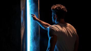 Man interacts with luminous panel in dark setting, exploring light and texture in an artistic expression photo