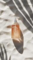 Clear liquid soap bottle with bubbles lying on textured surface illuminated by soft shadow patterns photo