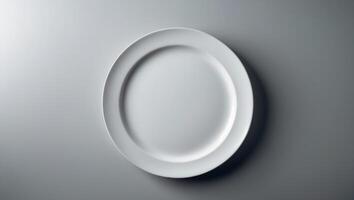 Empty white plate on a gray surface with soft lighting creating subtle shadows photo