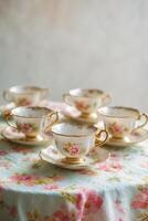 Elegant vintage tea set arranged on a floral tablecloth, showcasing fine craftsmanship and delicate rose patterns in a cozy setting photo