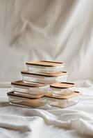 Stack of glass food containers with bamboo lids arranged on a soft surface in natural light photo