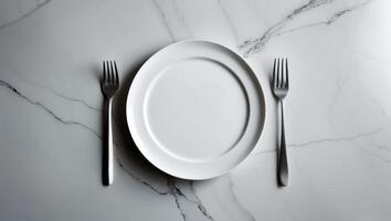 White plate and two forks on a white marble countertop, prepared for dining photo