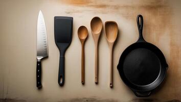 Kitchen utensils displayed on a wooden surface featuring a knife, spatula, wooden spoons, and cast iron skillet photo