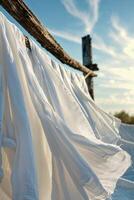 White fabric gently swaying in the breeze against a clear blue sky during the late afternoon hours photo