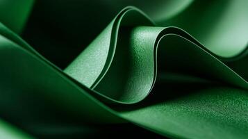 Green fabric displays elegant folds and curves under soft lighting in a close-up view, showcasing texture and depth in a creative setting photo