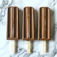 Three Chocolate Popsicles On Marble Surface photo