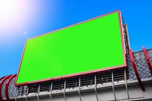 Blank green screen billboard on a building structure with a clear blue sky background, ideal for advertising mockups. photo