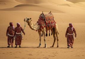 Walking Camel with Arab Men in Traditional Dress Across Desert Dunes photo