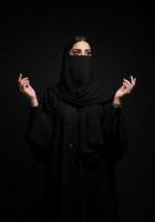Woman in Black Abaya and Niqab Posing Against Dark Backdrop photo