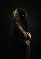 Saudi Arabian Gulf woman wearing a burqa and abaya looking at something with gestures of pride photo