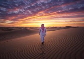Man Walking in Desert at Sunset with Colorful Sky and Sand Dunes photo