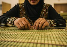 Weaving Traditional Mat with Straw by Woman Wearing Embroidered Dress photo