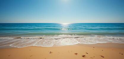 A serene beach with golden sand, clear blue sky, and gentle waves under the sun's bright rays photo