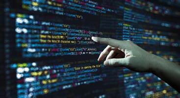 Human hand pointing at the abstract Modern tech of Programming code screen developer. photo