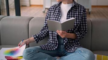 Caucasian woman lady at couch sofa busy at home girl female homeowner writing notes choosing colors palette colorful templates preparing for apartment renovation house design smiling happy at camera video