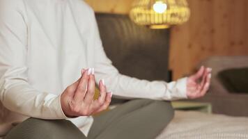 Comfortable clothes enhance relaxation as a woman practices gyan mudra during meditation, fostering inner peace and mindfulness in a serene bedroom setting video
