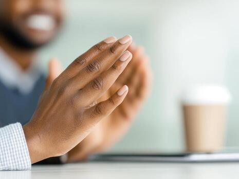 close up of hands clapping in creative workspace, expressing enthusiasm and collaboration. coffee cup is visible in background, adding to casual atmosphere photo