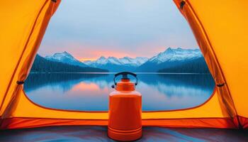 stunning view from tent opening reveals serene lake surrounded by majestic mountains at sunset, with orange kettle in foreground photo