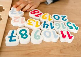 boy learns to count by laying out numbers from 1 to 20 on the board, boy 4-5 years old European appearance, at home in the living room sitting at the table, preparation for school photo