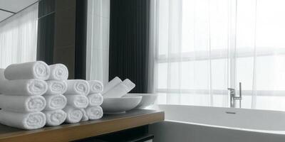 Freshly folded towels are neatly arranged on a bathroom table by a large window photo