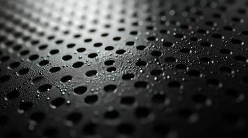 Water droplets on perforated black metal surface photo