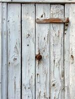 Weathered white wooden door with latch, peeling paint, rustic exterior photo