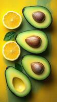 Halved avocados and lemon slices on vibrant yellow-green backdrop photo