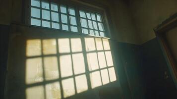 Sunlight streams through a high window in an old, dilapidated building, casting shadows on the wall. photo