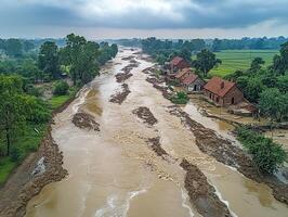 Flooded river through rural village, cloudy sky, aerial view photo