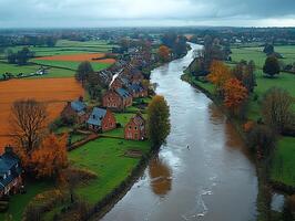 River flowing through autumnal village with colorful fields in background photo