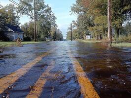 Flooded suburban street with houses, trees, and utility poles in background photo