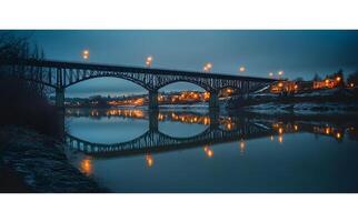 Illuminated Bridge Reflecting in Calm River Water at Dusk photo
