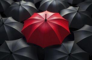 Red umbrella standing out from crowd of black umbrellas. photo