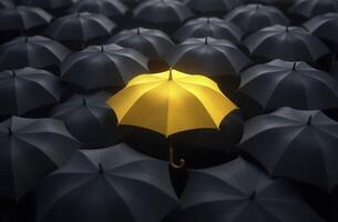 Yellow umbrella standing out from crowd of black umbrellas shows uniqueness and individuality photo