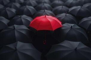 Red umbrella standing out from the crowd of black umbrellas photo