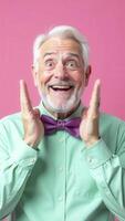 Excited senior man showing excitement and happiness on pink background photo