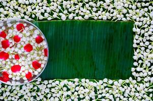 Flowers in water bowl for blessing with jasmine on empty space of banana leaf background for Thailand Songkran festival background. photo