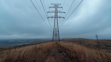 Electric pylons carrying power across rural landscape with dirt road and river photo