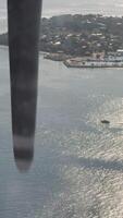 view from the water airplane window to the rotating propellers of the engine of a local airlines plane flying over the islands of Maldives, blue sky video