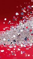 Silver glitter cascading over red festive, forming shimmering glitter, holiday background. Vertical format photo