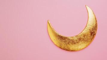 Golden crescent moon decoration against soft pink background creating a calming atmosphere for various design purposes photo