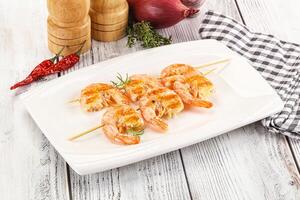A plate with shrimp and vegetables on skewers photo