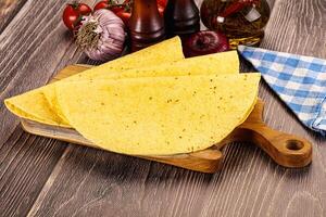 Three tortillas on a cutting board with tomatoes and other ingredients photo