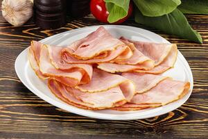 A plate of sliced ham on a wooden table photo
