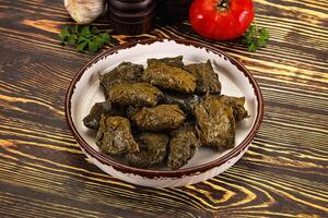 A bowl of green olives and tomatoes on a wooden table photo