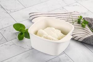 A bowl of yogurt sits on a counter next to a towel photo