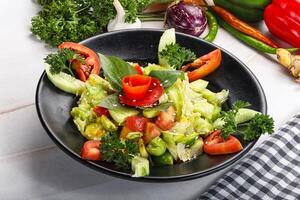 A bowl of salad with vegetables and tomatoes photo